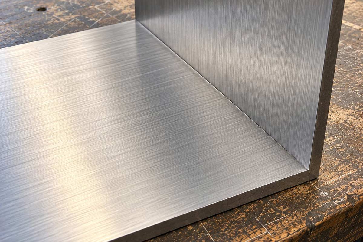 Deux tôles d'inox brossé grain 220 orientées perpendiculairement, montrant l'effet de sens du brossage
